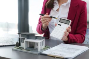 Real estate professional with pen and calculator in hand